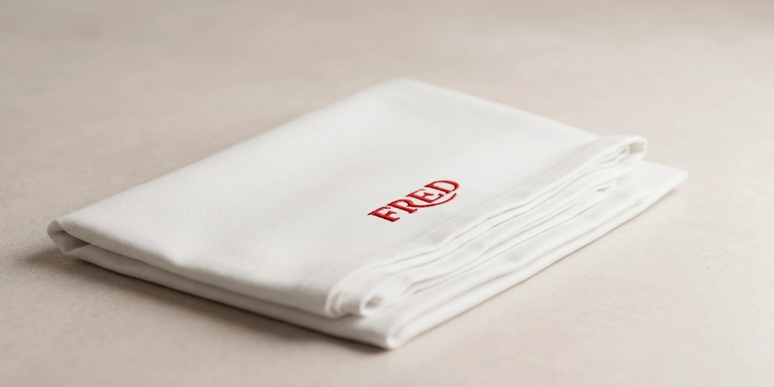 Monogramme brodé sur textile de luxe pour Fred — personnalisation artisanale par Graphiplus